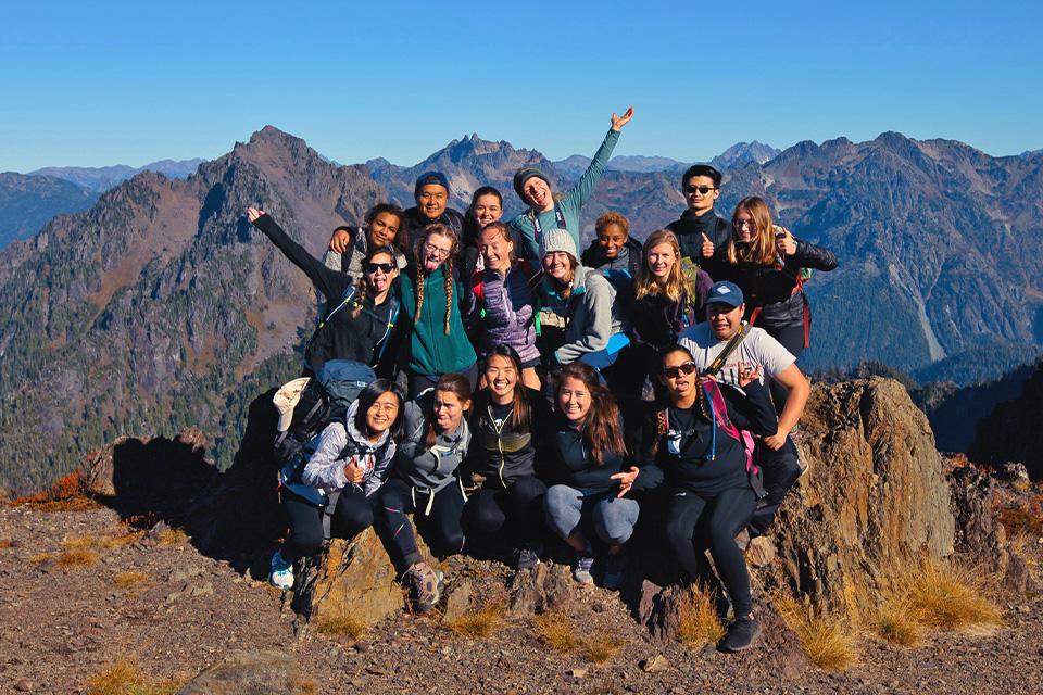 More than a dozen SPU students in the Outdoor Club have gathered on a mountain overlook 